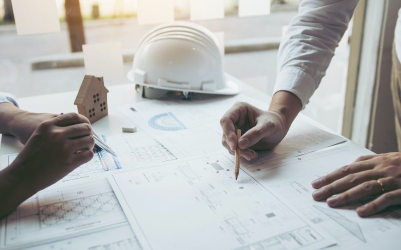 Engineering man showing blueprint detail for people buying house.