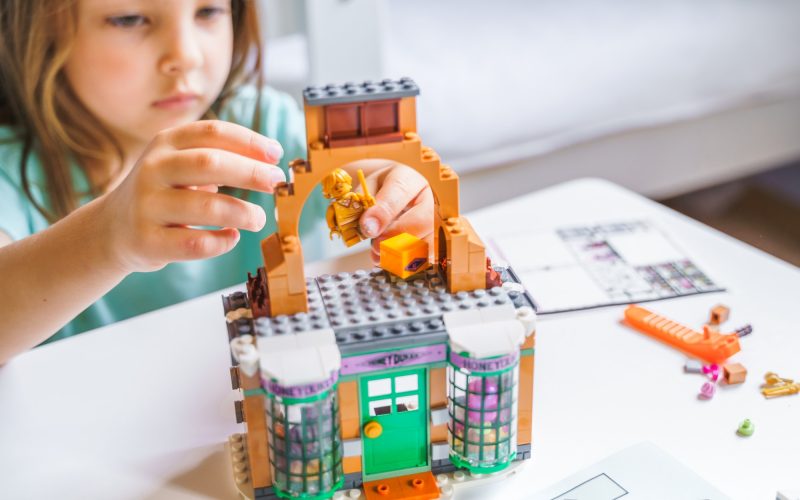 Girls, sisters play kids constructor, build house Lego Harry Potter from bricks, blocks by assembly