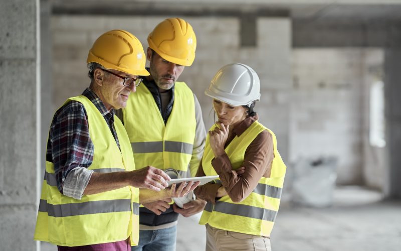 Three caucasian engineers discussing over digital tablet on the construction site